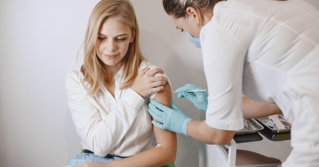 What Is a Vitamin B12 Injection, and How Does It Work? 1 Person sitting while a nurse administers a B12 injection in their arm.