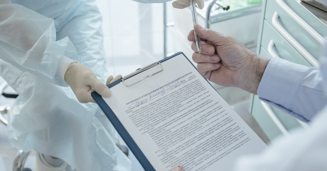 Outdated Booking Systems Are Driving Patients to Competitors 1 A patient signing a paper consent form with a pen.