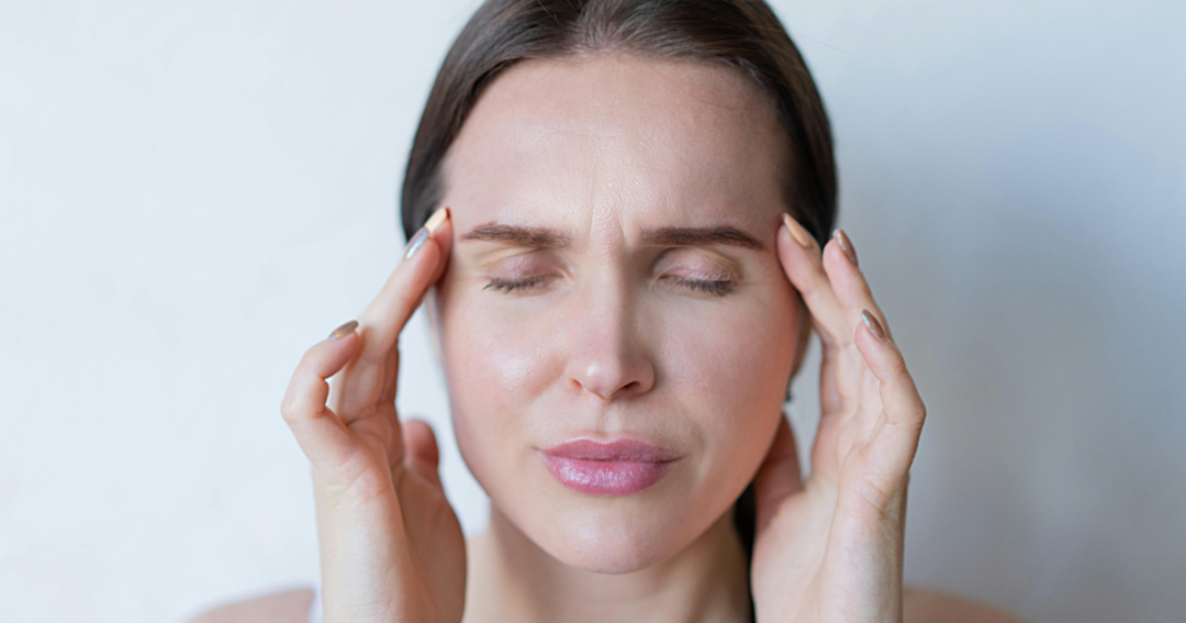 Botox for Chronic Migraine in the UK: Treatment, Benefits, and Patient Guidance 1 A woman holding her head in discomfort, showing signs of a migraine attack.