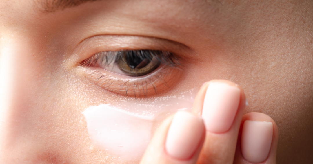 A client gently applying eye cream under their eyes as part of a skincare routine.