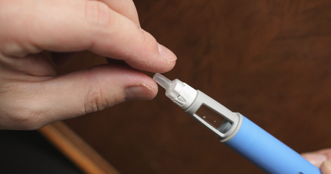 Patient preparing to inject Ozempic (semaglutide) with a prefilled pen, holding the pen and inspecting the dose.