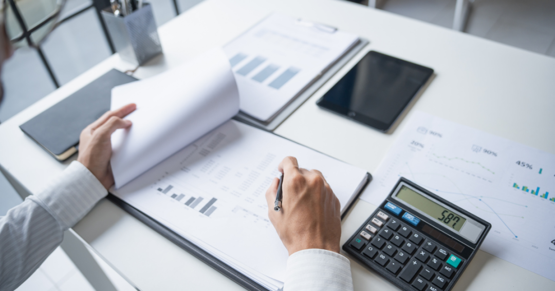 An accountant sat at a desk reviewing paperwork and working through financial calculations.