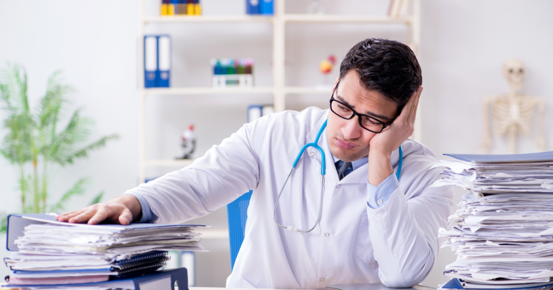 How Consent Form Software Can Help Prevent Costly Mistakes in Your Clinic 1 Practitioner feeling stressed while managing piles of paper consent forms in the clinic.